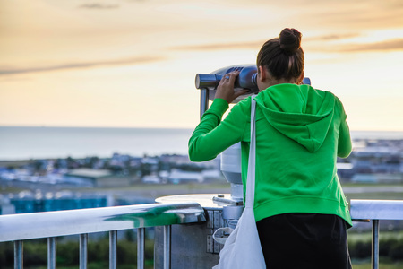 Young girl looking through a coin operated public binoculars in Reykjavik Icelandの写真素材