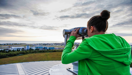Young girl looking through a coin operated public binoculars in Reykjavik Icelandの写真素材