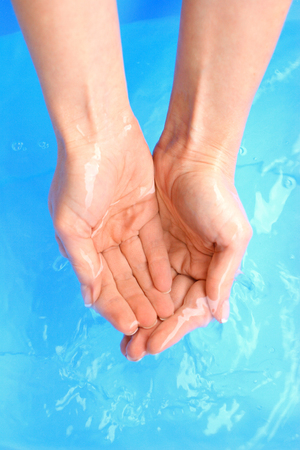 Washing hands in water, macro, blue backgroundの写真素材