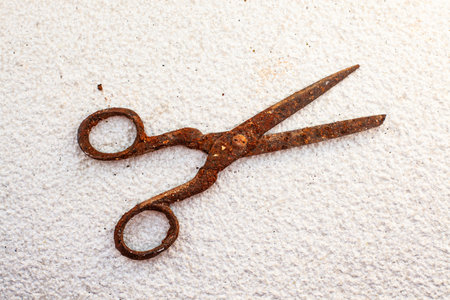 Old vintage scissors covered in rust on white stone background - isolatedの写真素材