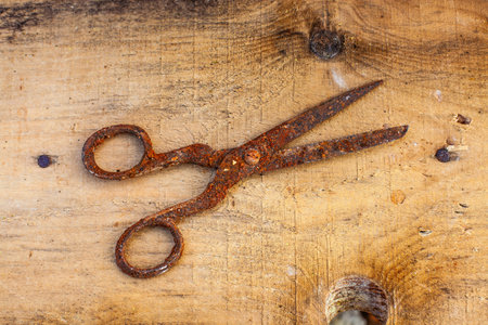 Old vintage scissors covered in rust on wooden boardの写真素材