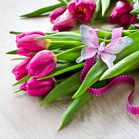 Pink fresh tulips flowers and a butterfly spring festive backgroundの写真素材