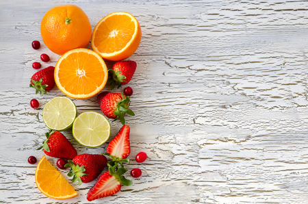 Orange, lime, strawberries, cranberries on copy space backgroundの写真素材