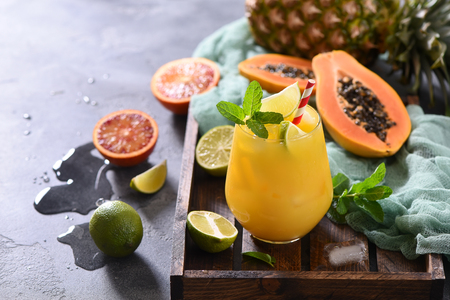 Fresh cold drink cocktail or lemonade with tropical fruits, papaya, pineapple, lime, juicy summer beverageの写真素材