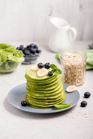 Healthy breakfast, spinach pancakes with blueberries, vegetarian food on white backgroundの写真素材