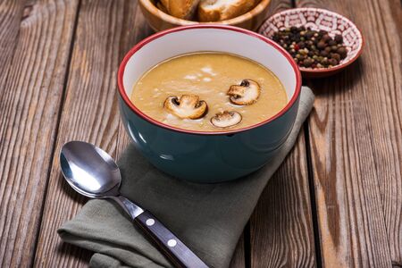 Champignon mushroom cream soup over wooden rustic background, delicious vegetable soup, healthy vegetarian and vegan foodの写真素材