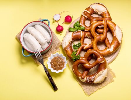 Pretzels and vegetables on yellow background, german traditional food, bavarian snack, european breakfast, oktoberfest conceptの写真素材