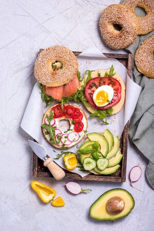 Bagel sandwiches with avocado, salmon, egg and vegetables, healthy snack, brunch or breakfast, top viewの写真素材