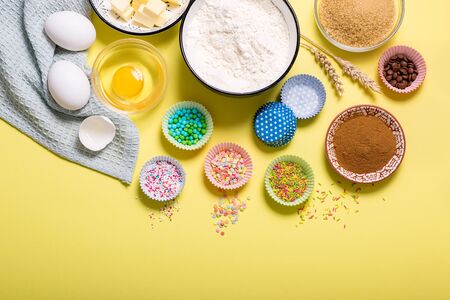 Baking ingredients for cupcakes or muffins on yellow copy space backgroundの写真素材
