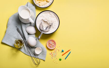 Baking ingredients for birthday cake on yellow copy space backgroundの写真素材