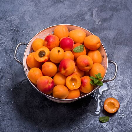 Fresh apricots in colander on dark background, summer fruits, refreshment, square imageの写真素材