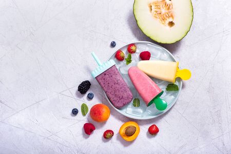 Yellow, purple, pink ice cream with fruits and berries, summer dessert, natural sweets, copy space backgroundの写真素材