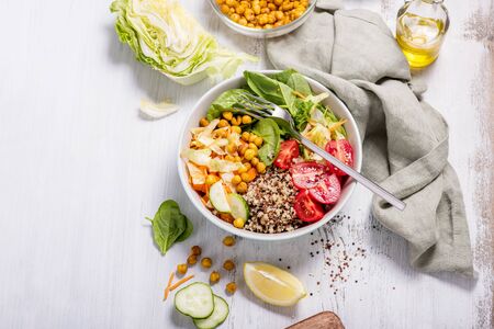 Quinoa salad with baked chickpeas, spinach, tomatoes, healthy vegan food, diet and clean eating concept, cooking at home, dinner and lunch ideas, white backgroundの写真素材