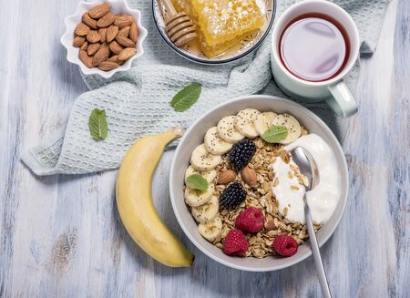 Healthy breakfast with granola, berries, honeycombs  and yogurt and a cup of tea, top view, overhead, healthy eating, morning snackの写真素材