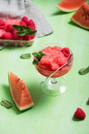 Watermelon sorbet or granita, refreshing summer dessert with strawberries and mint on blue backgroundの写真素材