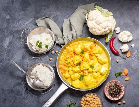 Vegetarian curry with cauliflower and chickpeas served in metal bowls with rice, healthy homemade vegan food, indian cuisine, clean eating concept,の写真素材
