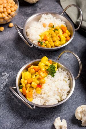 Vegetarian curry with cauliflower and chickpeas served in metal bowls with rice, healthy vegan food, indian cuisineの写真素材