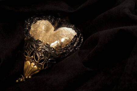 A shiny golden heart on black velvetの写真素材