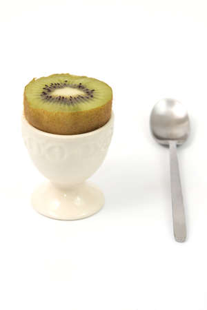 Kiwi in an eggcup with a spoon and a white backgroundの写真素材