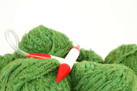 Green balls of wool with a knitting needle in front of a white backgroundの写真素材