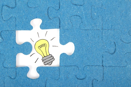 Missing blue piece of a puzzle with a bulb in front of a white backgroundの写真素材