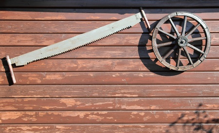 An old saw and a wheel on a wooden wallの写真素材