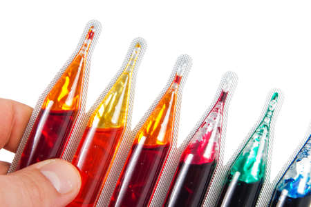 Detail of a hand holding food dye in different colors over a white background