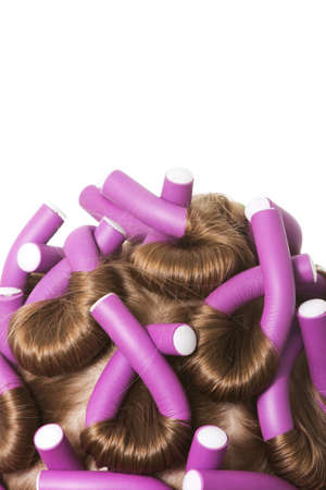 Dark blonde hair with purple curlers over a white backgroundの写真素材