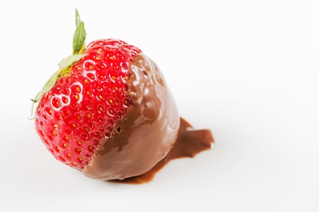 Closeup of a strawberry with chocolate on a white plateの写真素材