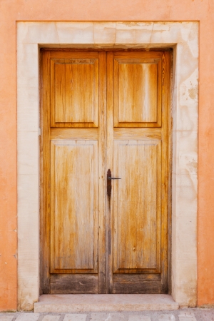 Old brown wooden door of a house entrance with an orange frontの写真素材