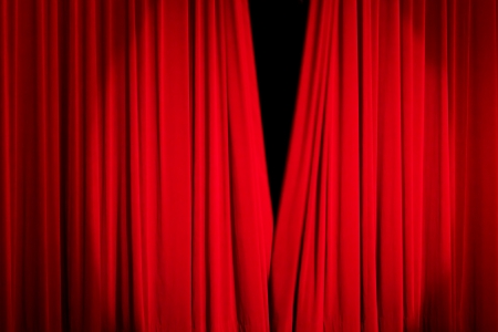 Red rising curtain with a light spot in a theatreの写真素材