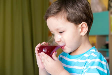 The boy is drinking red juiceの写真素材