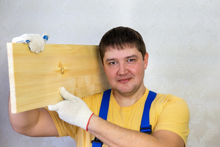 Male construction worker in a helmet and with a wooden boardの写真素材