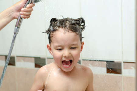 Boy washing hair with shampooの写真素材