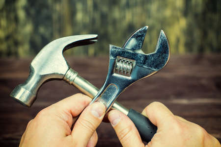 Hands hold a wrench and a hammerの写真素材