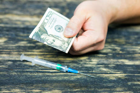 Hand gives money for a syringeの写真素材
