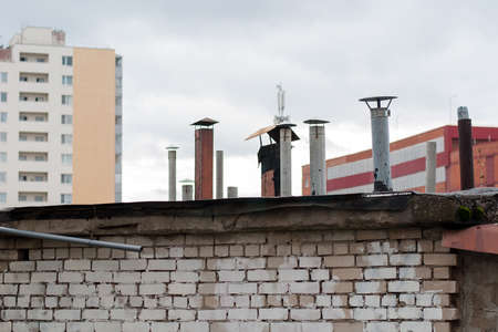 There are many chimneys on the roof of a residential building.の写真素材