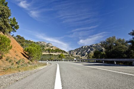 Road crossing Morrena Sierra Mountains of Despenaperros Natural Park Los Organos geological formations are at the natural monument in perspective and blue sky with light clouds is at backgroundの写真素材