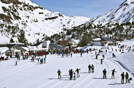 Somport Cross-Country ski resort in French Pyrenees at Spanish border and numerous skiers. Mountains bordered Aspe Valley and light cloudy sky  are at backgroundのeditorial素材
