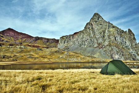 Peak Anayet 2575 m and Vertice Anayet 2559 m at left, and the tent in border of Lake of plateau at foreground, Spanish Pyrenees, Aragon, Spainの写真素材