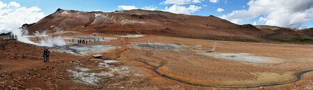 Reykjahlid, Icland ? ?? July 15, 2018. Panoramic view at Hverarond hydrothermal site in Northern Island. People follow walk between hot sources, fumaroles, mud sweaters, solfataras. Namafjall mountain is at background.のeditorial素材