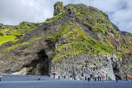 Vik I Myrdal, Iceland 23 July, 2018 People climbing The basalt columns of Reynisfjall mountain in Southern Iceland. Black sand of Reynisfjara beach in is at background.のeditorial素材