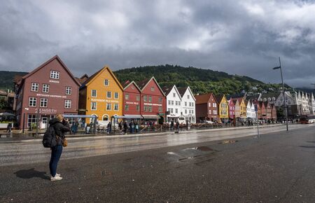 Bergen, Norway-July 27, 2017 Girl tourist talking picture of Hanseatic buildings of Bryggen, a World Heritage Siteのeditorial素材