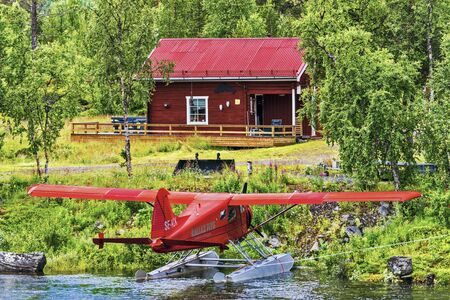 Norrbotten, Sweden - August 2, 2017 Red color wooden house in the forest and the hydroplane in the...