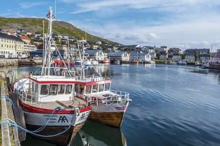 Honningsvag, Norway - August 10, 2017  The bay and Honningsvag city in Mageroya island seen from the harbor, two fisher boats are at foreground.  Nordkapp Municipality in Finnmark county.のeditorial素材