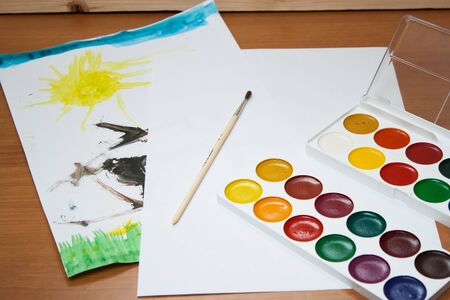 Children's drawings, a clean sheet and ink drawing with a brush on the table. Children's everyday life.の写真素材
