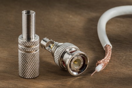 BNC connector for transmitting high-frequency signal and a piece of shielded cable on the wooden background.の写真素材