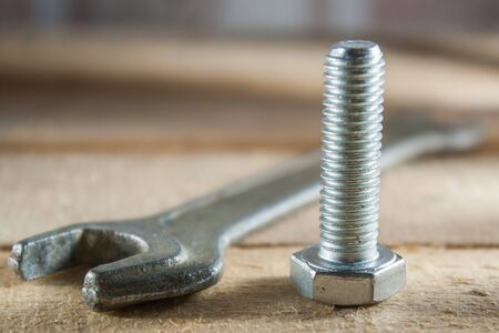 Old wrench and bolt lying on a wooden background.の写真素材
