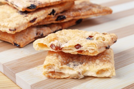 Puff cookies with raisins on a cutting board made of bamboo stripes.の写真素材