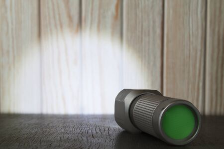 Bright LED flashlight shines on the wooden surface.の写真素材